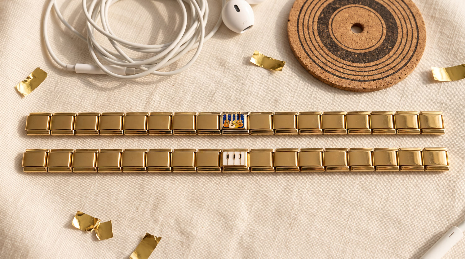 Goldene Italian Charm Armbänder mit Gitarre- und Klavier-Charm, umgeben von Kopfhörerkabel, Konfetti und Vinyl-Untersetzer